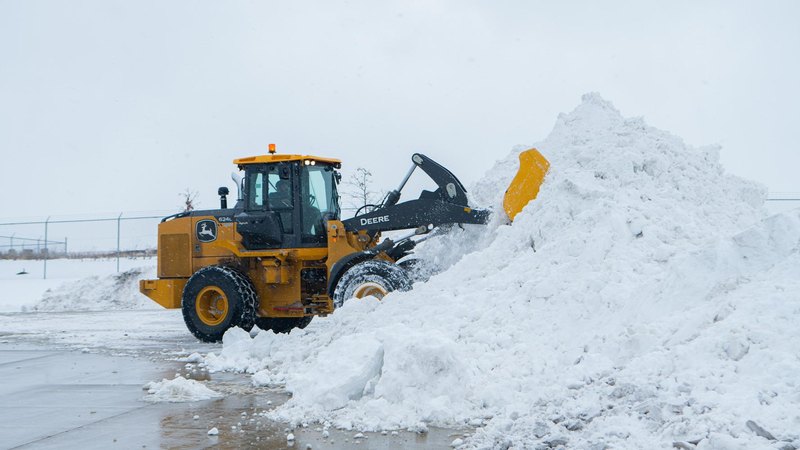 Full-size wheel loader stacking a snow pile to recover parking capacity