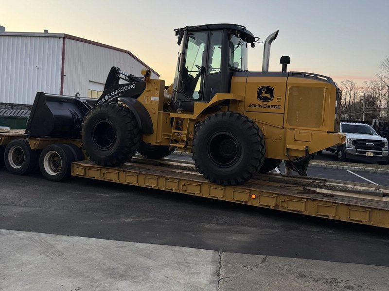 Wheel loader with a Clear Landscaping box pusher loaded on a trailer for transport between sites