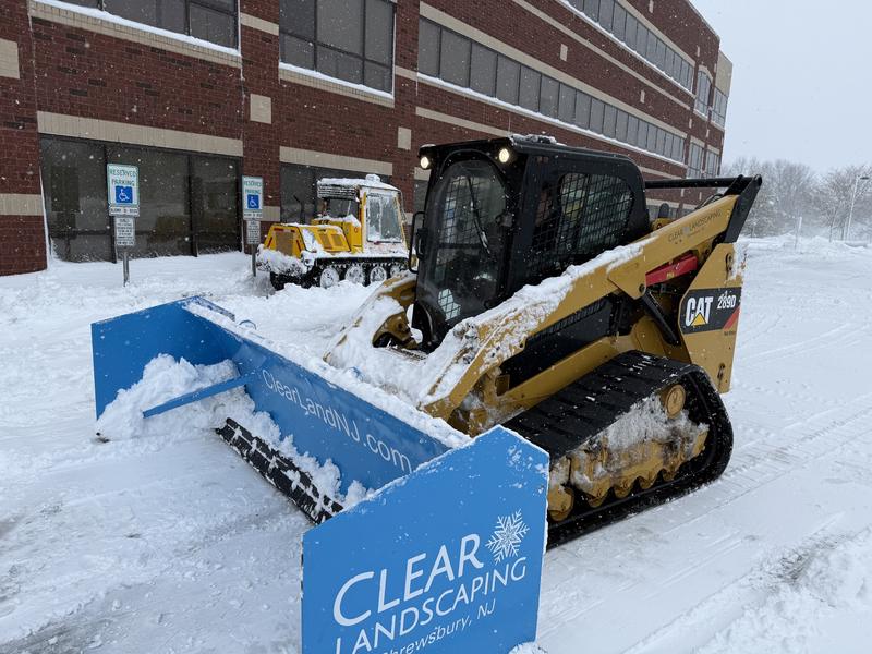 Skid steer clearing an accessible building entrance and walkway